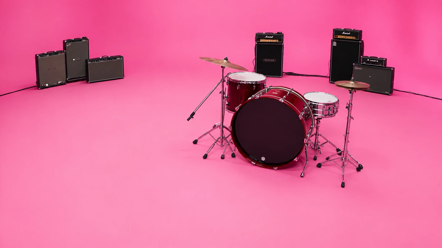 The empty hot-pink studio with a red drum kit and black amplifiers